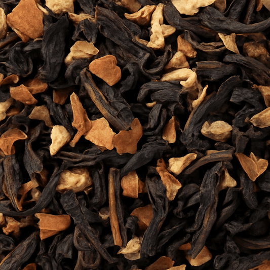 Close-up view of a loose leaf Masala Chai tea blend, showing a mix of black tea leaves and visible spice pieces such as cinnamon, ginger, and cardamom.
